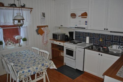 a kitchen with white cabinets and a table with a tablecloth at Orsastuguthyrning-Oljonsbyn in Orsa