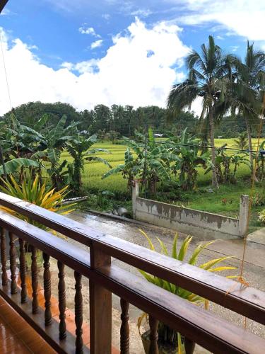 a balcony with a view of a field with palm trees at MIOKI HOMETEL in Batuan