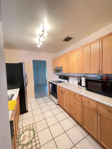 a kitchen with wooden cabinets and a black refrigerator at Sunset Charlotte - Home away from home in Port Charlotte