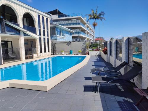 a swimming pool with chairs next to a building at Citadel Suite in Port Macquarie