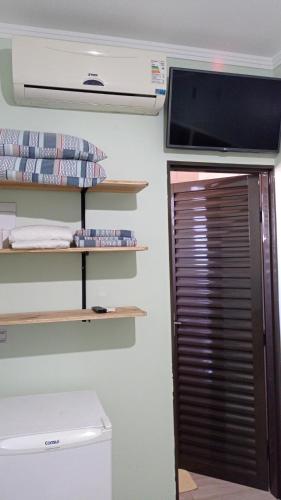 a room with a television and a closet with shelves at Pousada Menina Moça in Olímpia