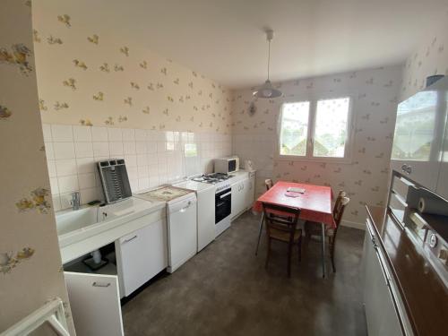 une cuisine avec une table et une cuisinière four supérieur dans l'établissement Maison Royan 70 m² avec jardin, proche plage et casino, quartier calme - FR-1-71-52, à Royan