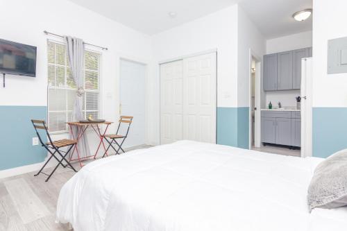 een witte slaapkamer met een wit bed en een tafel bij Home Miami - Wynwood area with backyard - Art District near to Beach in Miami