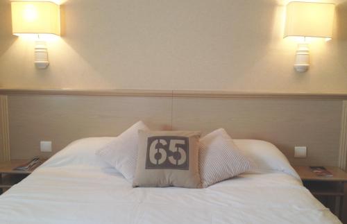 a bed with a pillow with the number on it at The Originals City, Hôtel Chantecler, Le Mans in Le Mans