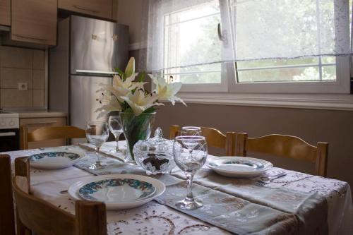 una mesa con platos y vasos y un jarrón de flores en Veria Ammos apartment to farm with treehouse en Ámmos