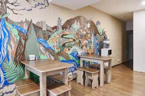 due tavoli in una stanza con un murale sulla parete di Moosica Hostel a Tbilisi City