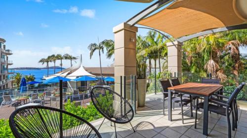 a patio with tables and chairs and a view of the water at Unit 21 - 3 Bed Part Ocean View in Terrigal