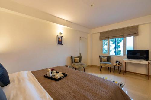 a hotel room with a bed and a television at Eastbury by VEO - Part of StayVista in Mashobra