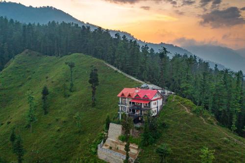 a house on top of a green hill with trees at Eastbury by VEO - Part of StayVista in Mashobra
