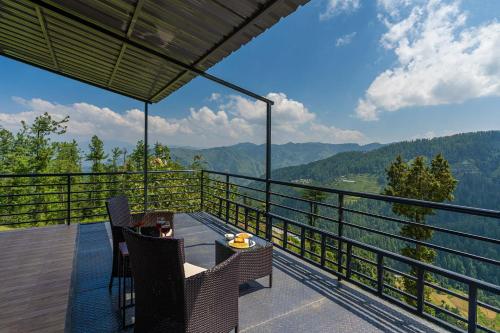 a balcony with a table and chairs and a view of the mountains at Eastbury by VEO - Part of StayVista in Mashobra