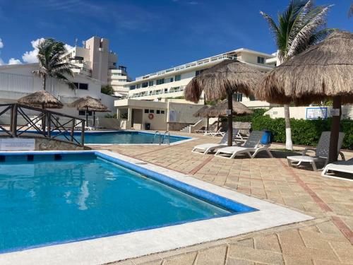 a swimming pool with umbrellas and a resort at Cancun Oceanfront, Entire Apartment in Cancún