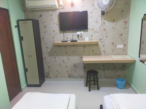a small room with a desk and a tv on a wall at Leaf Guest House in Kuantan