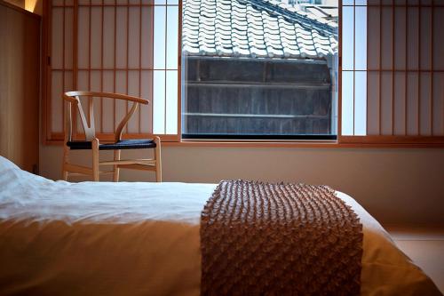1 dormitorio con 1 cama, 1 silla y 1 ventana en HOTEL和紡 en Nagoya