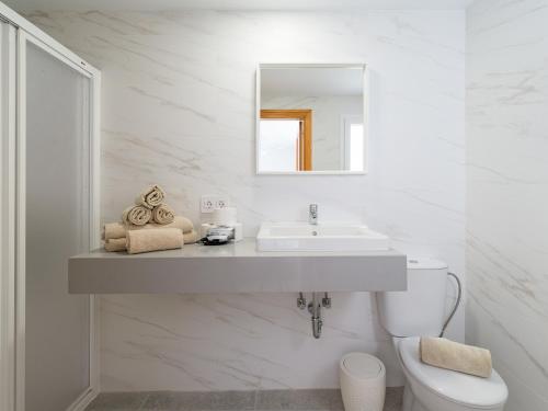 a white bathroom with a sink and a toilet at Granada II Apartments in Puerto Rico de Gran Canaria