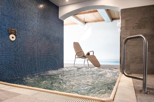 eine Whirlpool-Badewanne im Bad mit Stuhl in der Unterkunft Silvretta Parkhotel in Klosters