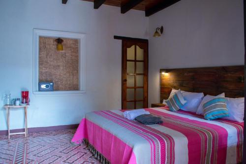 a bedroom with a large bed with a pink blanket at Arte Sano Hotel San Cristobal in San Cristóbal de Las Casas