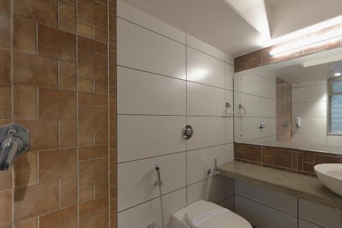 a bathroom with a toilet and a sink and a mirror at Hotel Ariana Residency in Mumbai