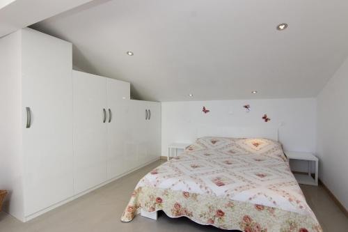 een witte slaapkamer met een bed en witte muren bij Apartment Pika Smokvina 2a in Vinišće