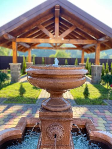 a water fountain in a yard with a pavilion at Hostynnyy Dvir Apartament Hotel & SPA in Slavske