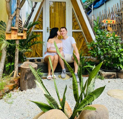 a man and a woman sitting in front of a house at Trầm Homestay in Thôn An Hòa