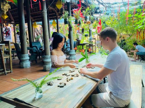 a man and a woman sitting at a table playing with rocks at Trầm Homestay in Thôn An Hòa