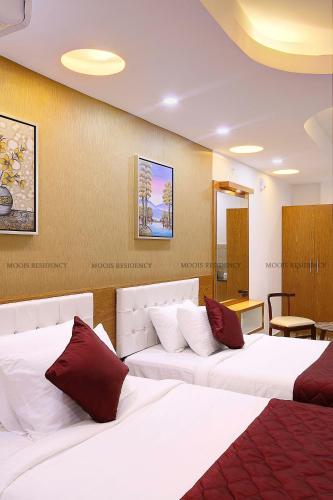 a hotel room with two beds with red pillows at Moois Residency ,Bangalore in Bangalore
