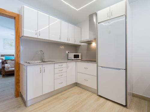 a kitchen with white cabinets and a refrigerator at Granada II Apartments in Puerto Rico de Gran Canaria