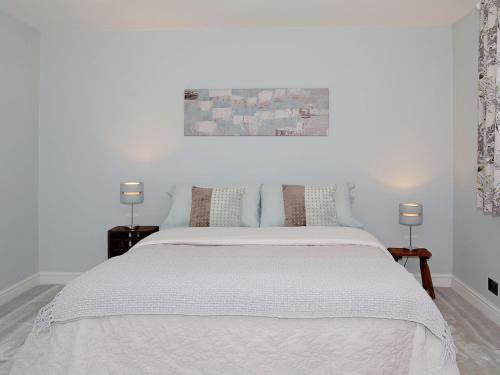 a white bedroom with a large white bed with two lamps at Ivy Cottage in Westfield