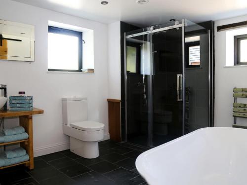 a bathroom with a toilet and a glass shower at Ivy Cottage in Westfield