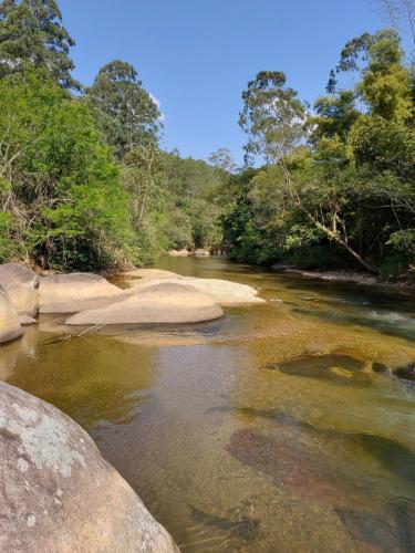 a river with rocks and trees in the background at Lumiar Eco Lodge - Chalé Pedra Riscada in Nova Friburgo