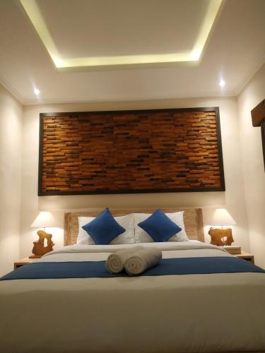 a bedroom with a large bed with blue pillows at Cahaya Guest House in Ubud