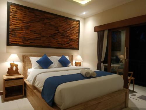 a bedroom with a large bed with blue pillows at Cahaya Guest House in Ubud
