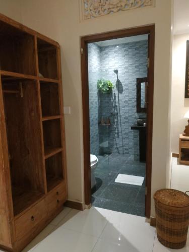 a bathroom with a toilet and a glass shower door at Cahaya Guest House in Ubud