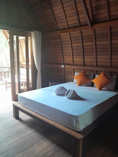 a large bed with orange pillows in a room at La Paparrucha Bali in Pemuteran