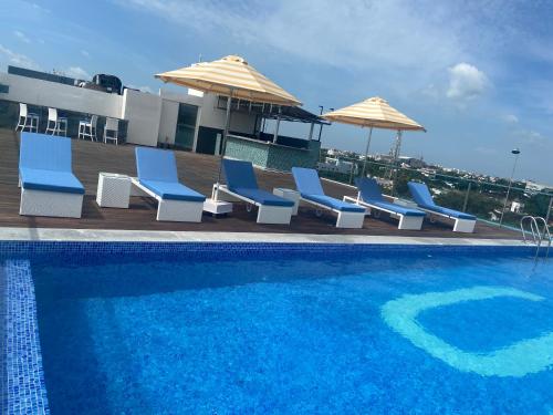 a swimming pool with blue chairs and umbrellas at Svenska Design Hotel Kakinada in Kākināda