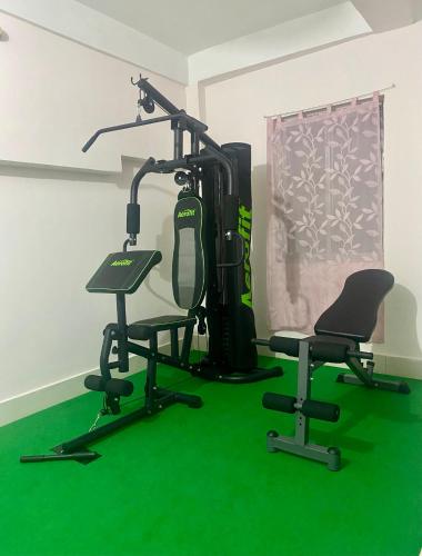a room with a gym with green carpet and two chairs at Tridhara HomeStay in Guwahati