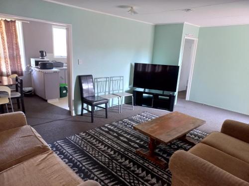 uma sala de estar com um sofá e uma televisão de ecrã plano em Mount Budget Accommodation em Tauranga