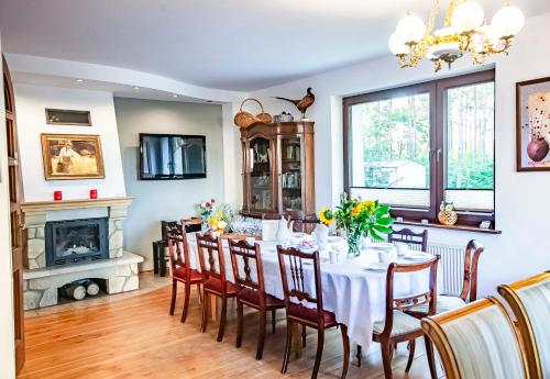 een eetkamer met een tafel en stoelen en een open haard bij Weekend house w lesie, na Kaszubach in Rybaki