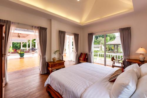 ein Schlafzimmer mit einem großen Bett und einem Balkon in der Unterkunft Phi Private Villa: Luxury Thai with Riverview in Chiang Mai