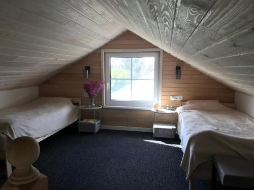 a attic bedroom with two beds and a window at Cozy holiday house with sauna and entertainment 