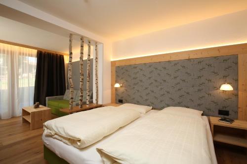 a bedroom with a large white bed and a wall at Residence Garni Stella in San Vigilio Di Marebbe