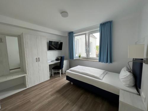 a bedroom with a bed and a desk and a window at Gästehaus Blauth in Cuxhaven