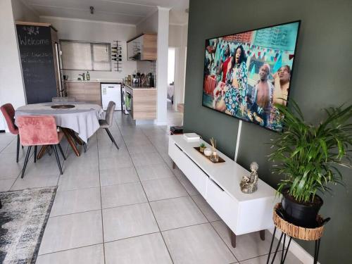 a living room with a table and a tv on the wall at Loadshedding Equipped 2-Bed Apartment in Waterfall, Waterfall City in Midrand
