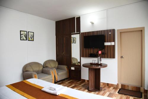 a hotel room with a bed and a table and a tv at PHIBHA VILLA in Shillong