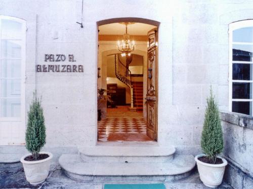 une entrée à un bâtiment avec deux plantes en pot dans l'établissement Pazo Almuzara, à Boborás