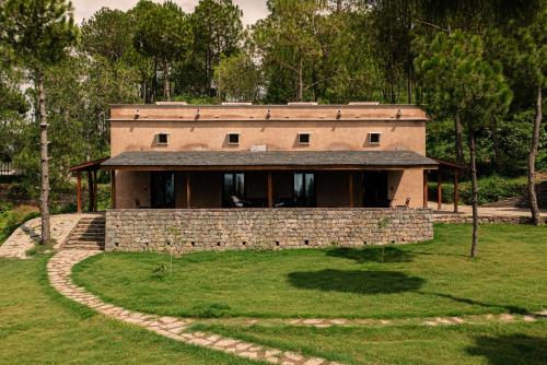 a house in a field with a stone wall at Amaya Life Kasauli in Kasauli
