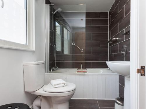 a bathroom with a toilet and a tub and a sink at Kitcat Cottage in Dartmouth