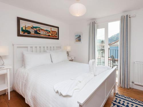 a white bedroom with a white bed and a window at Kitcat Cottage in Dartmouth