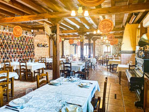 un restaurante con mesas, sillas y botellas de vino en Posada Real de Carreteros en Casarejos