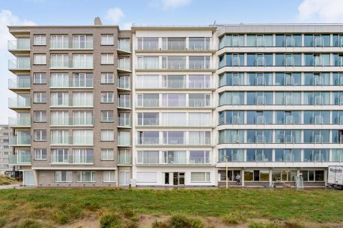 ein Mehrfamilienhaus mit einer Rasenfläche davor in der Unterkunft Duin én zeezicht te Zeedijk Oostduinkerke in Oostduinkerke